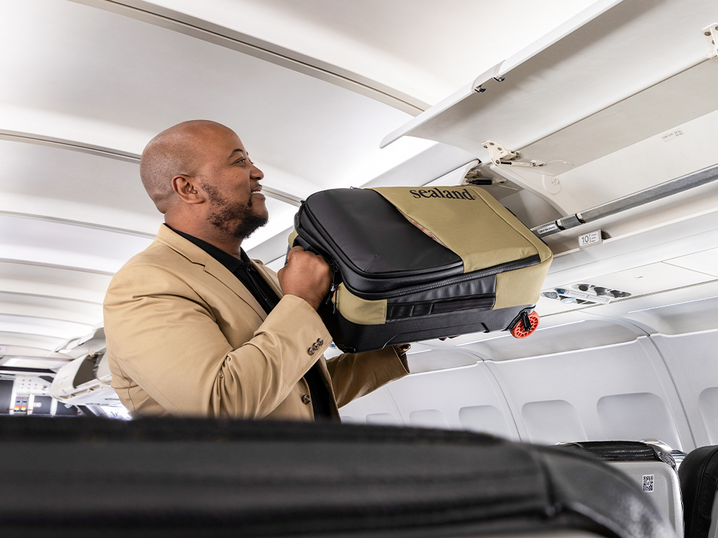 Passenger stowing cabin bag in LIFT overhead compartment